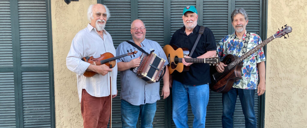 BeauSoleil members standing with their instruments in front of French doors.