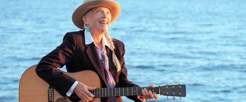 Laurie Lewis singing by a body of water.